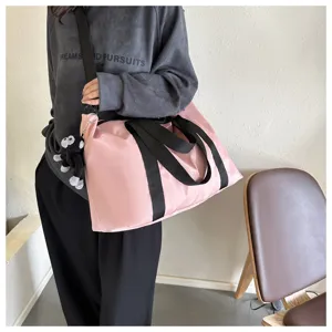 Large capacity pink travel tote bag with black handles and cute monkey plush charm detail.