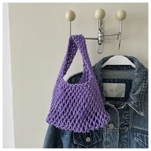 Close-up of the purple knitted mesh handbag showing hollow crochet texture and woven handle.
