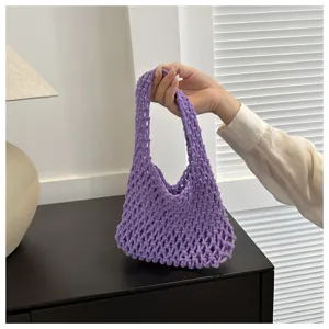 Close-up detail of a stylish purple knitted mesh handbag, featuring a chic hobo net design.