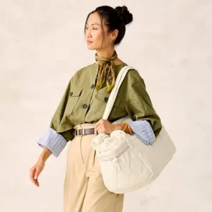 Detail view of a large white quilted tote bag worn by an Asian model in a studio setup.