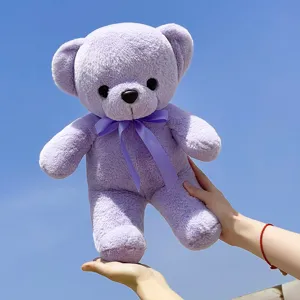 Close up detail of purple plush teddy bear with cute ribbon bow, soft stuffed animal toy.