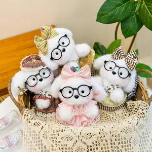 Close-up detail of cute white plush puppy keychains wearing round glasses and pretty bows in a basket.