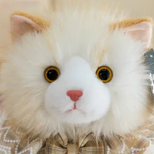 Gros plan détail d'une jolie poupée chat en peluche avec col à nœud papillon écossais.