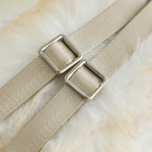 Gros plan détaillé d'une sangle tissée beige avec boucles métalliques carrées sur fourrure