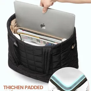 Detailed view of the black quilted puffer tote bag interior, showing padded laptop compartment.