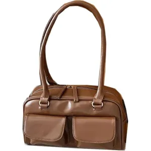 Close-up details of the brown leather shoulder bag, highlighting dual front pockets and zippers.