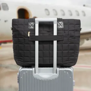 Black quilted tote bag with luggage sleeve, stylish travel commuter shoulder bag for women.