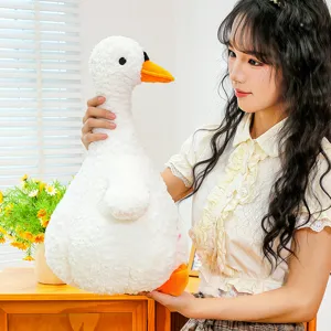 Close-up detail shot of the cute white plush duck toy held by a model in a warm indoor setting.