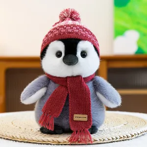 Close up view of the cute plush penguin toy wearing a red knitted hat and scarf detail.