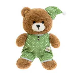 Cute brown teddy bear plush toy wearing green polka dot pajamas and sleeping hat for kids