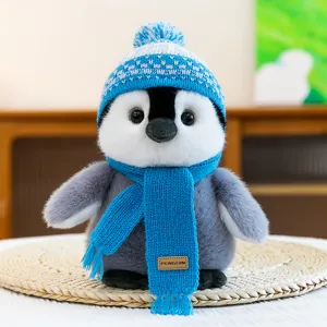 Close-up of cute winter penguin plush toy featuring blue knitted hat and cozy scarf details.