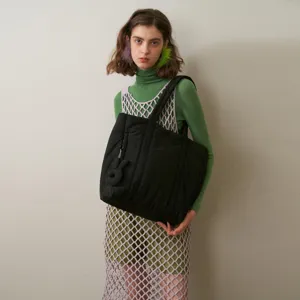 Detail view of a black quilted padded tote bag for women, large capacity shoulder commuter bag.