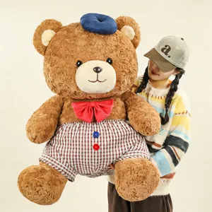 Cute large brown plush teddy bear with blue hat, red bow tie and plaid shorts detail shot.