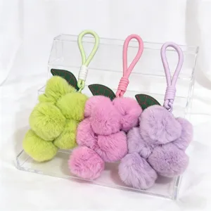 Close-up detail of plush grape bag charms showing fluffy faux fur texture and green leaf accent.