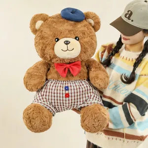 Cute brown teddy bear plush toy with blue beret red bow tie and plaid shorts detail.