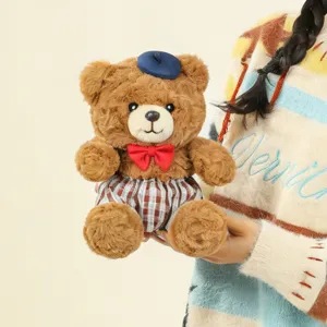 Cute brown teddy bear plush close up with blue beret, red bow tie and stylish plaid shorts.