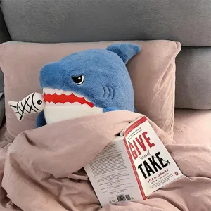 Cute shark plush pillow stuffed animal toy with fish bone, cozy bedroom bed decoration detail.