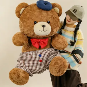 Giant teddy bear plush toy with blue beret, red bow tie, and cute checkered shorts.