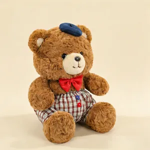 Detailed shot of a cute brown plush bear toy wearing a blue beret and chic plaid overalls.