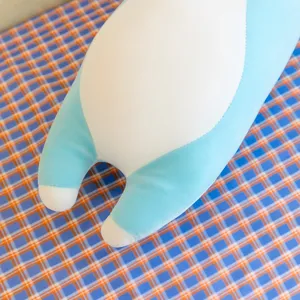 Close-up detail of blue and white plush rabbit toy pillow, soft fabric texture and cute feet.