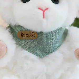 Dettaglio peluche pecorella bianca con pelliccia morbida e sciarpa verde con etichetta.
