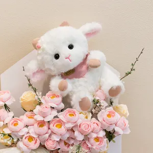 Dettaglio di un peluche agnellino bianco con bavaglino rosa tra rose rosa e gialle.