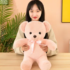 Soft pink teddy bear plush toy with cute ribbon bow detail in cozy indoor scene setting close up