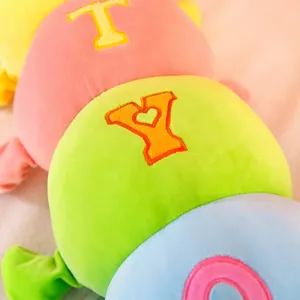 Colorful plush caterpillar toy detail, soft stuffed animal pillow with cute embroidered letters.