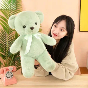 Plush green teddy bear toy doll with cute ribbon bow, soft stuffed animal for kids and hugging.