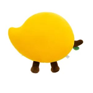 Détail de peluche avec forme de mango, tissu jaune doux, petites jambes brunes et feuille.