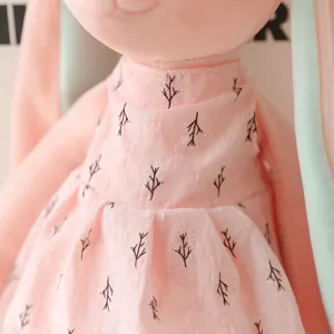 Cute plush rabbit toy detail close up showing soft pink dress texture and exquisite sewing.