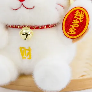 Cute white lucky cat plush toy detail, fluffy doll with gold bell and red embroidery character.