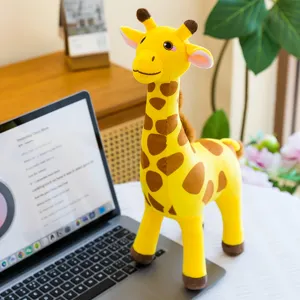 Creative cute giraffe plush toy standing on a laptop keyboard in a cozy desk setup.