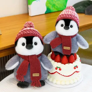 Cute winter penguin plush toy detail shot featuring knitted hat, scarf and a mini cake prop.