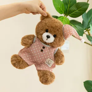Close-up of cute brown teddy bear plush toy wearing pink polka dot pajamas and sleeping cap.