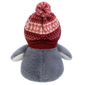 Detail view of a cute plush penguin doll wearing a red knitted winter hat with pom pom.