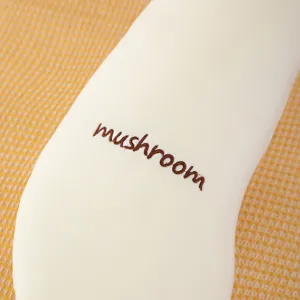 Gros plan détaillé du long oreiller champignon doux avec une belle broderie marron.