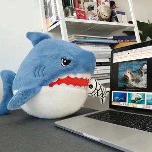 Detailed view of the cute blue shark plush toy biting a fish bone on an office desk.
