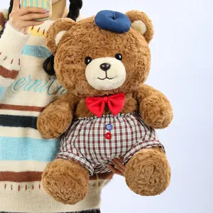 Cute teddy bear plush toy detail showing soft brown fur texture, blue beret and red bow tie.