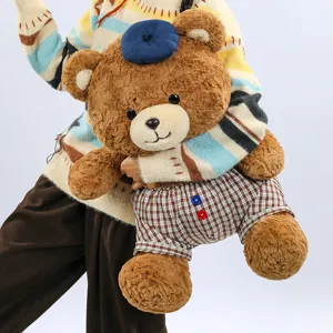Cute plush brown teddy bear toy with blue beret and plaid shorts, soft and huggable.