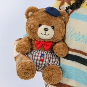 Close-up detail of cute brown plush teddy bear wearing blue beret and red bow tie.