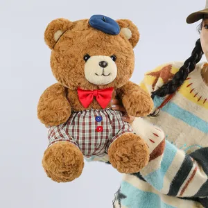 Cute brown teddy bear plush toy wearing blue beret and plaid overalls detail view showcase.