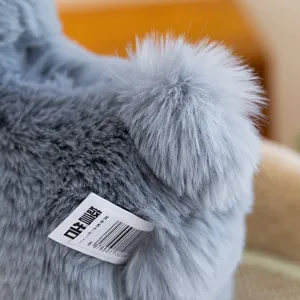 Grey plush alpaca toy detail view, fluffy tail texture and soft material close up shot.
