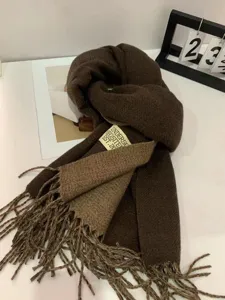 Detailed shot of a stylish brown winter scarf with tassels and label for cozy warmth.