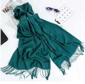 Detailed view of the dark green cashmere-feel fringed scarf, showing soft texture and cozy styling.