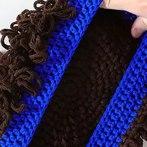 Detail view of the handmade knit wig hat with funny curly hair texture and blue brim.