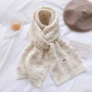 Detailed close-up view of cozy knitted cashmere winter scarf with lovely pink speckles and tag.