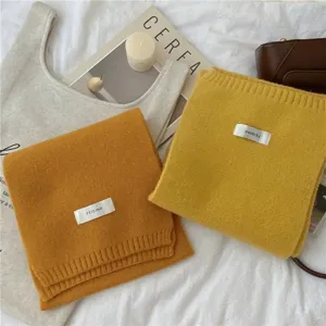 Vue de détail d'écharpes en tricot douillettes en jaune, stylisées avec des accessoires.