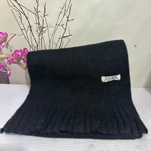 Close-up detail of the black plush winter scarf showing soft fuzzy texture and fringe edge.