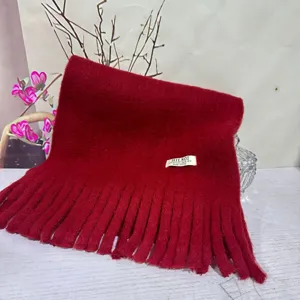 Red plush tassel scarf detail showing soft fabric and neat fringe edge texture.